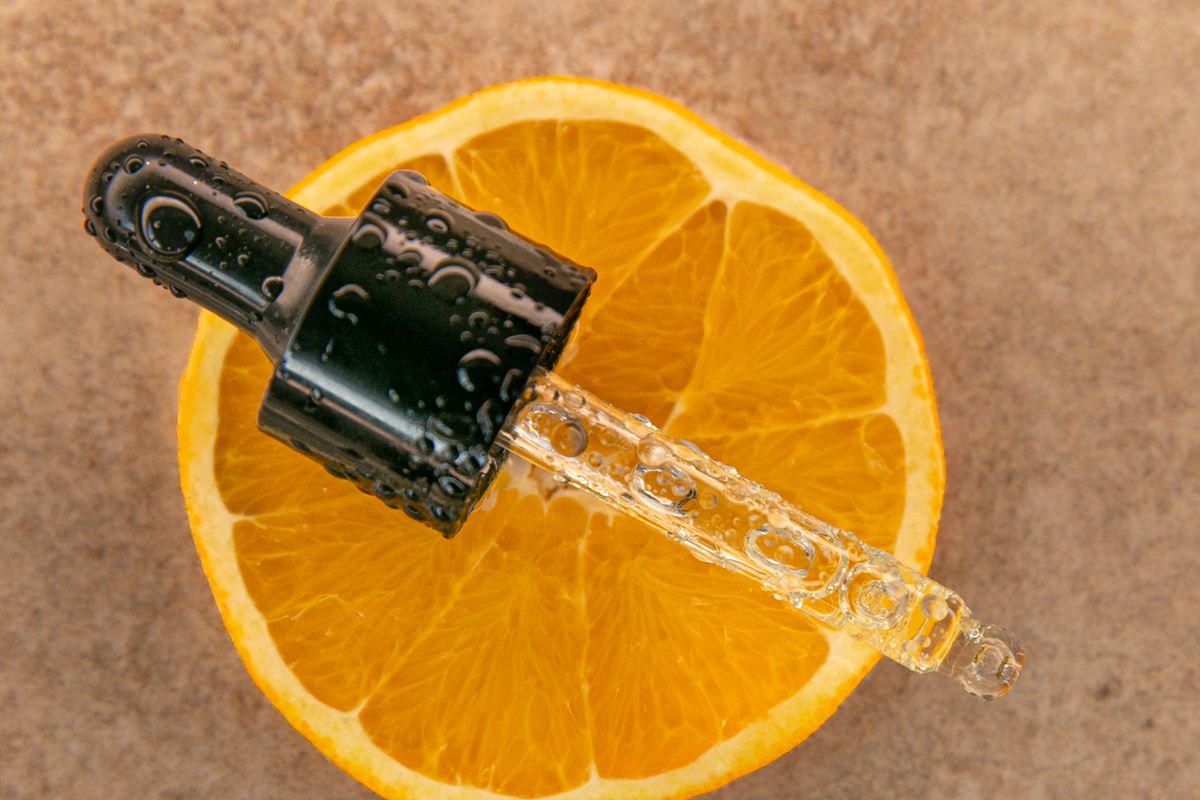 Glass serum dropper resting on a cut citrus fruit